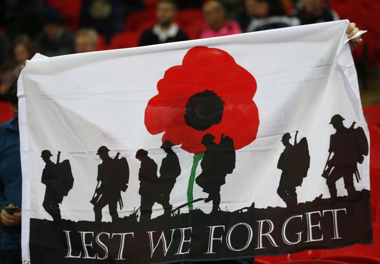 FILE - A Friday, Nov. 11, 2016 file photo showing a banner with the silhouette of troops and a large red poppy with the words 'Lest We Forget' is held up by a fan prior to the start of the World Cup 2018 Group F qualification soccer match between England and Scotland at Wembley stadium in London. FIFA is set to relax the rules that ban teams from commemorating non-sporting events at soccer matches in response to high-profile disputes with British associations over honoring war dead. (AP Photo/Frank Augstein, File)